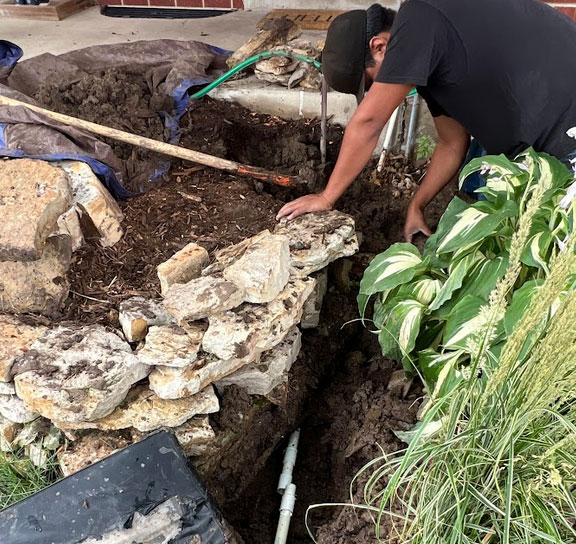 our tech is working on a sprinkler repair by replacing a broken irrigation pipe